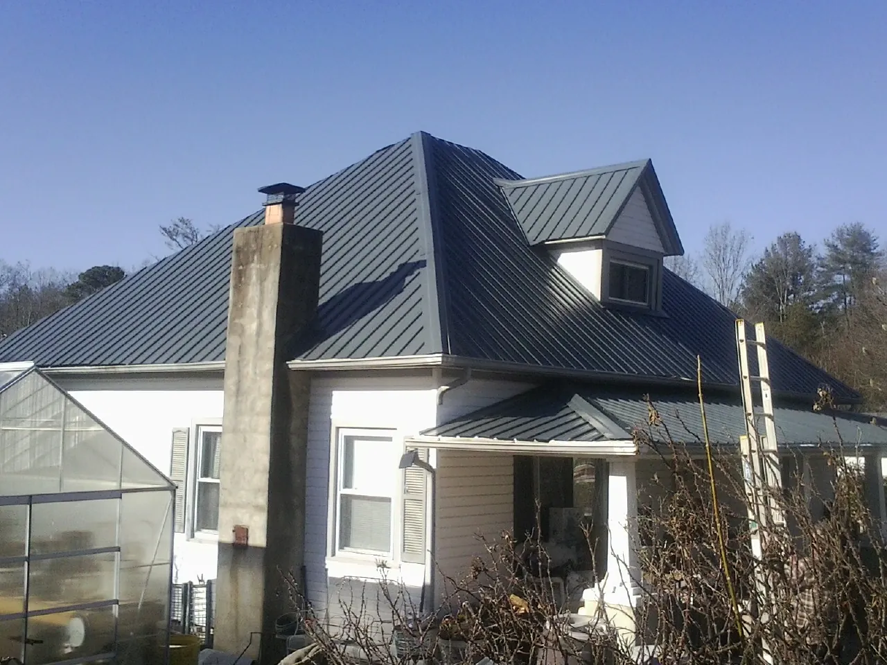 Dark blue standing seam metal roof on a white farmhouse with dormer — Slate & Tile Roof Repair by Roofing Brothers in Sewickley
