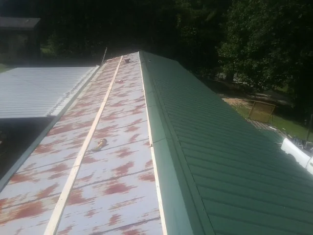 Old rusted panels beside newly installed green metal roofing — Wind Damage Roof Repair by Roofing Brothers in Sewickley