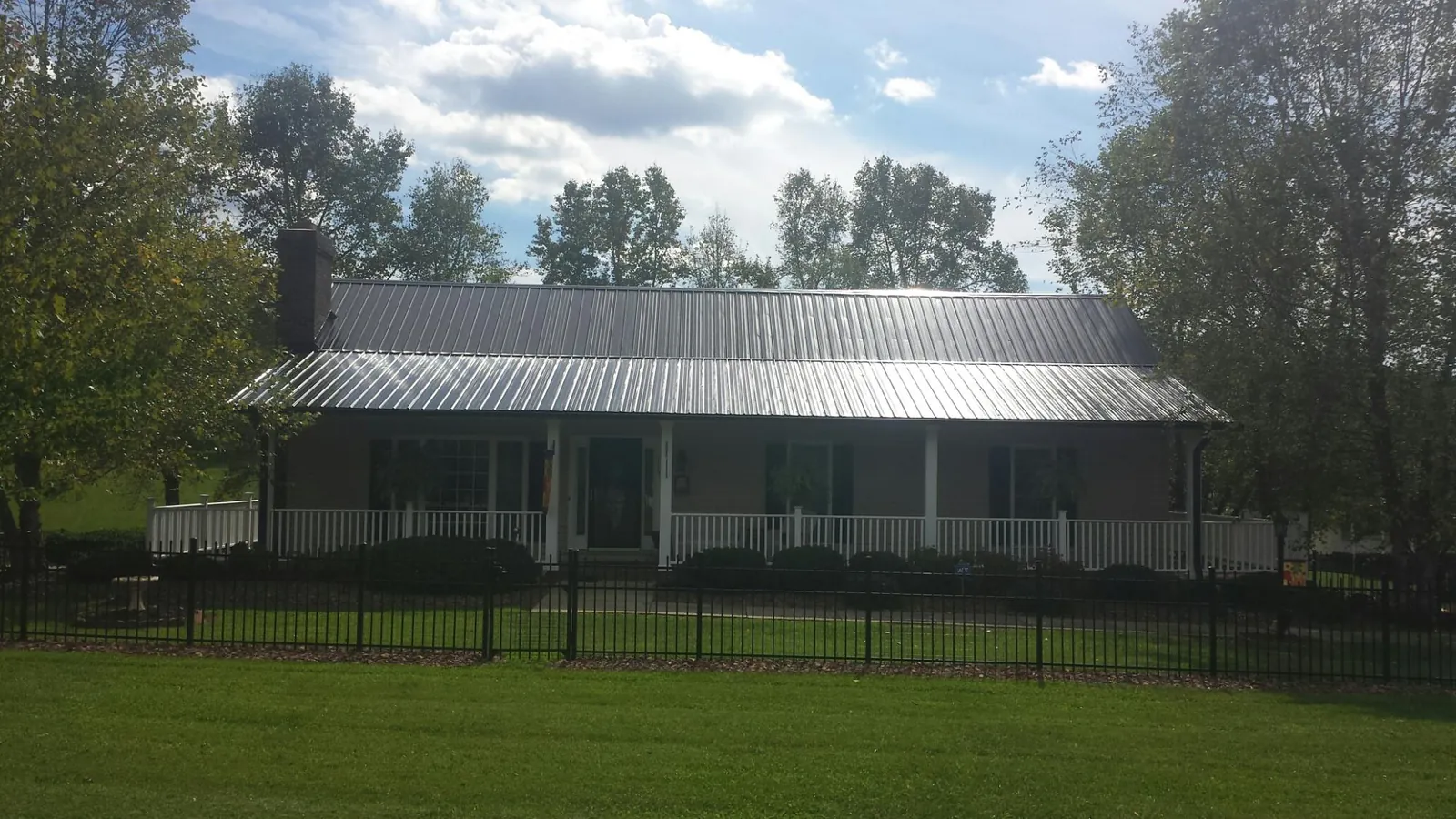 Gray metal roof on a brick ranch with a full width front porch — Gutter Guard Installation work by our crew in Sewickley