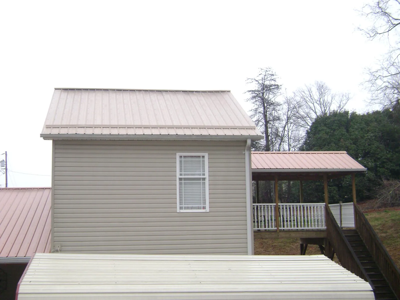 Tan metal roofs on a two story addition and attached porch, from a Roof Replacement job in Sewickley