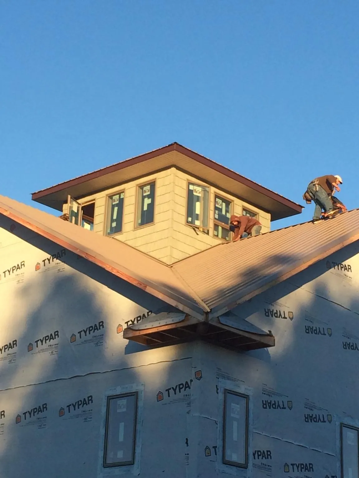 Roofers working around a rooftop cupola on a new metal roof at sunset — Roof Waterproofing in Sewickley by Roofing Brothers